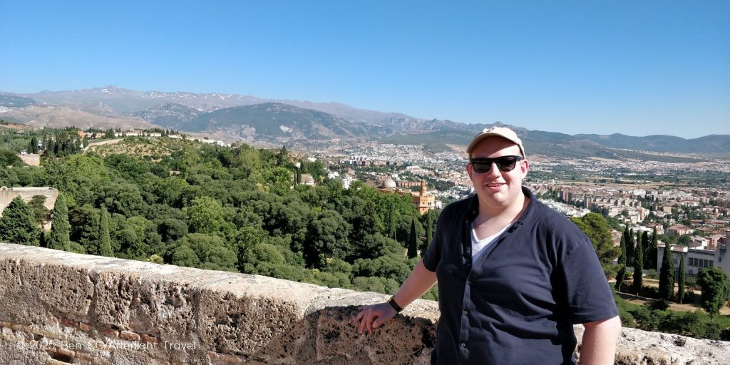 The author smiling at the top of the Alhambra citadel in Granada, Spain, with sweeping views of the Sierra Nevada National Park behind him.